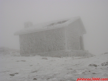 El refugio, cubierto de escarcha, entre la niebla.