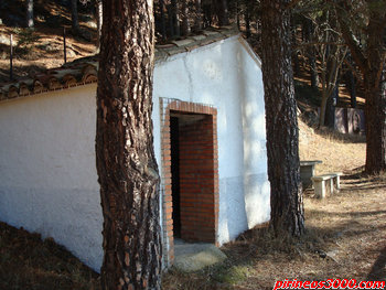 Exterior del refugio, se aprecia una de las mesas con el banco y al fondo la bon