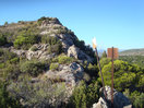 10- Con vistas hacia la cota que precede a, El Ollero, rebasamos los visibles mástiles metálicos, y en llegar a la redondeada roca que se observa en el centro, donde colocamos un hito de piedras, abandonamos la cresta cimera y seguimos hacia la derecha, bordeando parte de la cota, llegando en breve a la entrada de la cavidad.